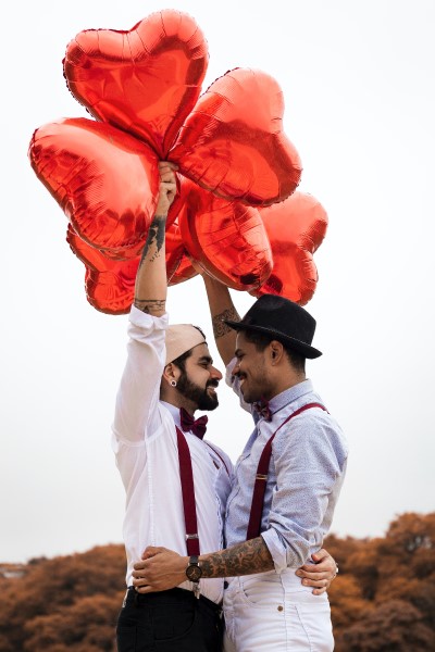 Happy couple holding red heart balloons.